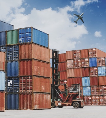 Containers stacked on top of each other with a plane in the sky