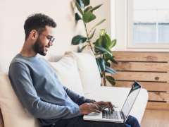 a person working on a sofa with their laptop on their lap